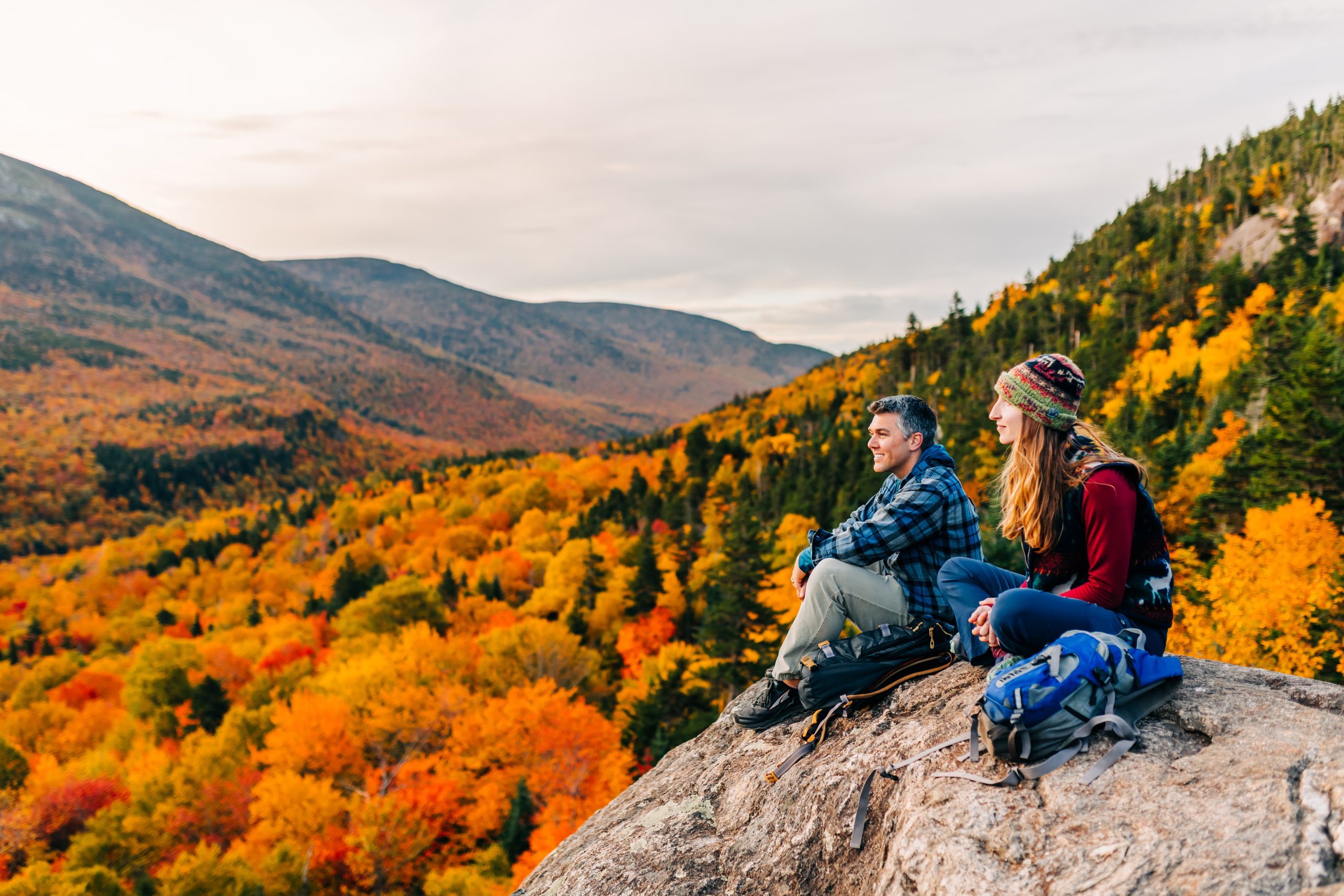 two people on cliff overlooking foliage view